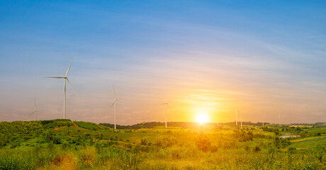 Obraz premium wind turbine with green grass field at beautiful sunset sky background. renewable energy