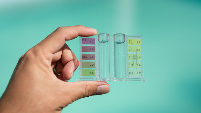 A swimming pool service person is holding a water tester kit which is using for measuring pH value and Chloring concentration.