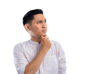 Pensive Asian Muslim man looking aside with doubtful and skeptical expression isolated on white background. Ramadan and Eid Fitr celebration concept