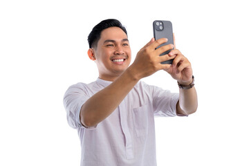 Happy Asian Muslim man looking at mobile phone screen, reading good news isolated on white background. Ramadan and Eid Fitr celebration concept
