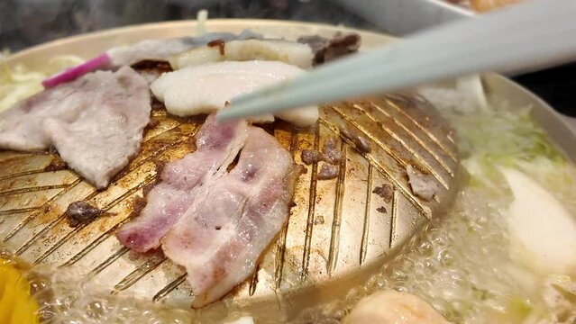Close-up at a piece of sliced pork meat is grilling on BBQ pan, BBQ food meal. 4k footage.