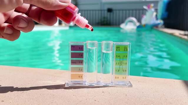 Action of a person hand is using Phenol red droplet to drop into sample water for measuring the pH value. Swimming pool water treatment service and maintenance. 