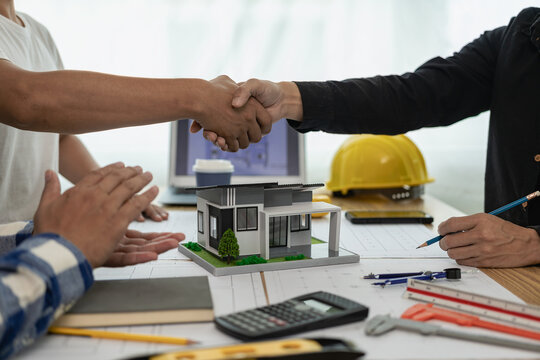 Architect and construction engineer holding hands while working for teamwork and cooperation concept after completing an agreement on construction site. Close-up pictures
