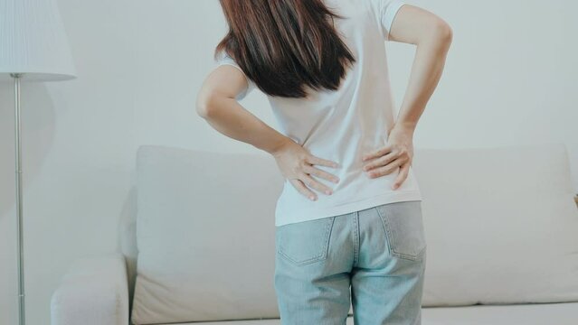 woman having back body ache during sitting on Couch at home. adult female with muscle pain due to Piriformis Syndrome, Low Back Pain and Spinal Compression. Office syndrome and medical concept