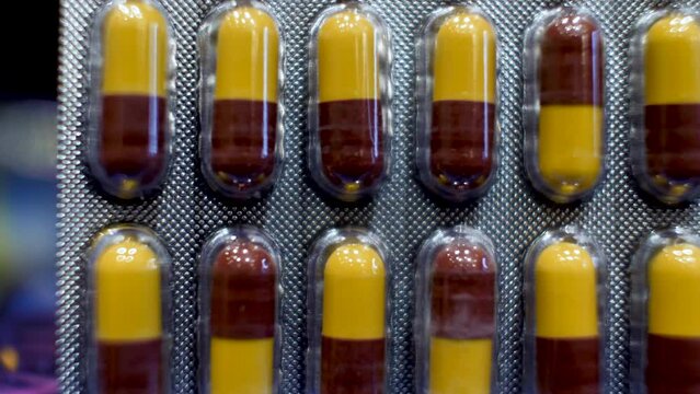 A close-up view of Amoxicillin Capsules as the dark red and yellow components are delicately arranged into their original packaging, encapsulates the essence of medical care and treatment.