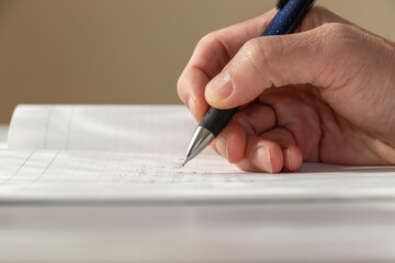 ノートにペンで何か書き込む人の手