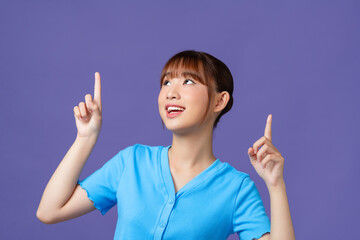 Young Asian woman showing and pointing up with fingers, inviting use link isolated purple background