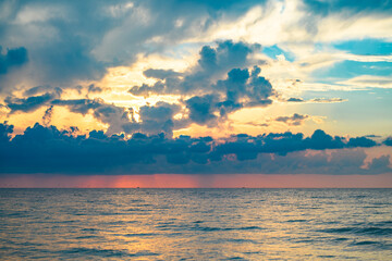 Fototapeta na wymiar Calm sea with sunset sky and sun through the clouds over. Sunrise sea on tropical beach. Landscape of beautiful beach. Beautiful sunset at sea. Ocean sunset on sky background with colorful clouds.