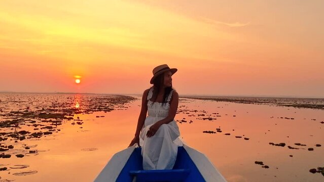 The sea of red lotus, Lake Nong Harn, Udon Thani, Thailand, a woman in a boat at sunrise at the Red Lotus Lake in the Isaan