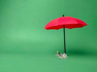 Red umbrella held by transparent tape on a green background