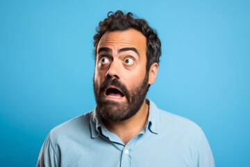 Handsome man with beard surprised and shocked while looking right on blue background
