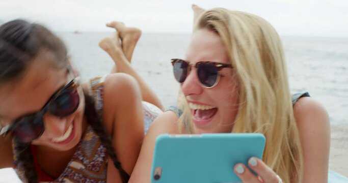 Friends, phone and happy women at a beach laughing at social media, gif or meme while bonding. Smartphone, comic and people relax at sea with app for streaming funny text, conversation or online joke