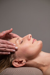 Fototapeta na wymiar Caucasian woman undergoing a head and face massage procedure. Vertical photo.