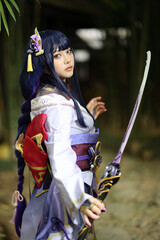 Portrait of a beautiful young woman game cosplay with samurai dress costume on Japanese garden