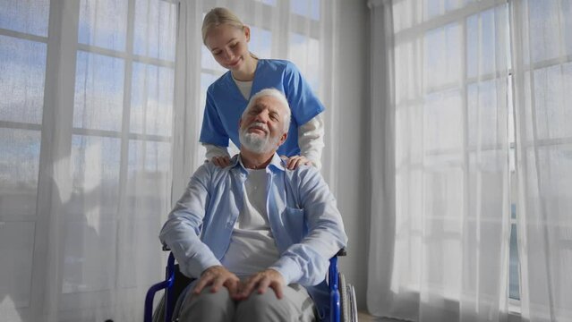 Nurse massage neck to paralyzed man. Senior male in wheelchair enjoying massage at home. Medical worker provide care support help. Living with legs paralysis, special needs people retirement concept.