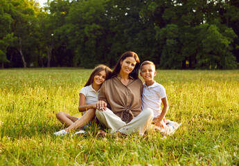 Happy family spending time in nature. Portrait of a mother and children in the park in summer....
