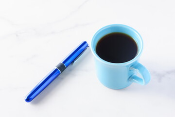 コーヒーが入ったマグカップとペン
