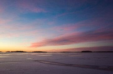 Glowing pink and yellow morning sky over frozen lake Mälaren at sunrise, Västerås, winter in Sweden