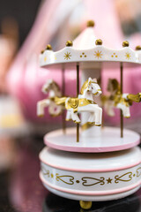 White and pink music carousel with gold horses on dark background