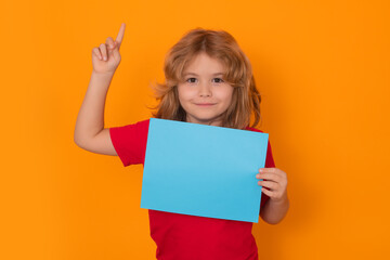 Fototapeta na wymiar Kid showing blank banner on yellow background, pointing finger up. Advertising billboard, placard. Child hold empty color blank sheet of paper, copy spase. Poster for your text information.