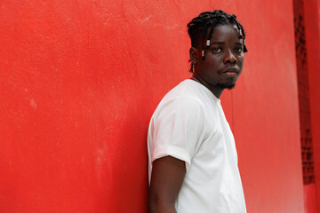 African American man with unique hair looking at camera. Standing at red background