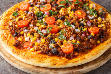 Hot Tex Mex taco pizza with ground beef, salsa, cheddar cheese and Mexican spices close-up on a wooden board on the table. Horizontal