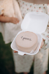 a small bento cake with the inscription 1 year in the hands of the mother for a little daughter