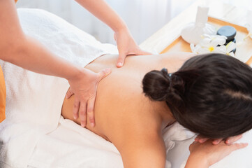 Fototapeta na wymiar Hands of masseur massaging back of relaxed woman with aromatherapy essential oil on massage table.