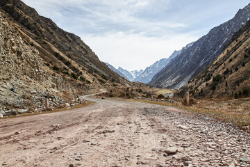 Country road leading to mountains. Kyrgyz republic, Kyrgyzstan. Mountain natural landscape in brown colors, scenery