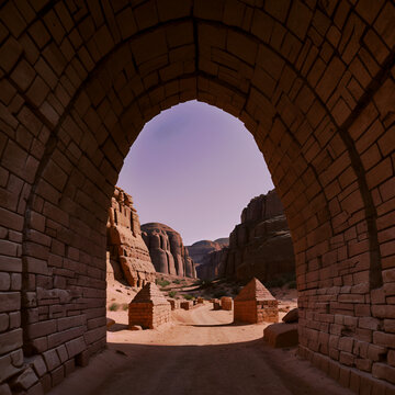 A tunnel made of brick with a view of tombs in the desert