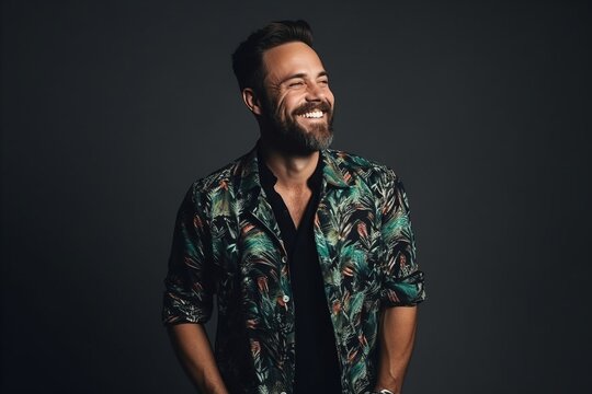 Portrait of a handsome smiling man in colorful shirt over dark background.