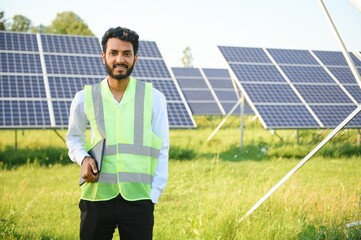 male engineer checks a photovoltaic (solar) plant and uses a recording tablet. Indian Man in uniform holding tablet.