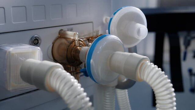 Close up tubes of life support or artificial ventilation device standing in operating room of modern hospital with advanced equipment for surgery. Bright operating block in clinic or medical facility.
