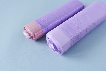 Rolls of purple plastic garbage bags isolated on a blue background.