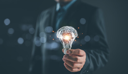 Businessman holding illuminated lightbulb, idea, innovation and inspiration with glowing virtual...