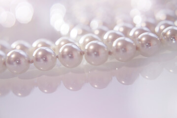 A necklace of pearls lying on white glass
