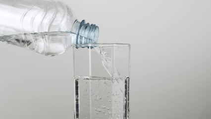 Close up pouring fresh clean drinking water into glass from plastic bottle - Powered by Adobe