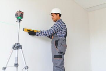 An Indian worker works in an empty apartment. A man in a uniform makes repairs inside the building