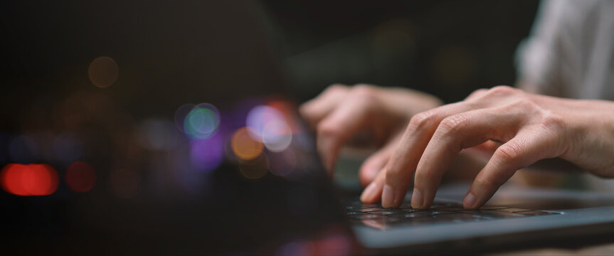 Businesswoman hand working on a laptop, bokeh blurred for text copy space, image size horizontal