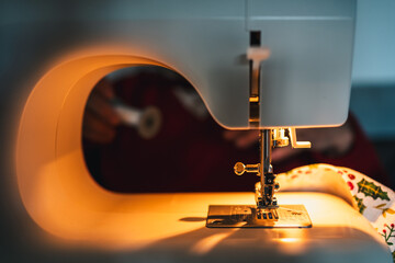 detail of sewing machine on with light getting ready by seamstress