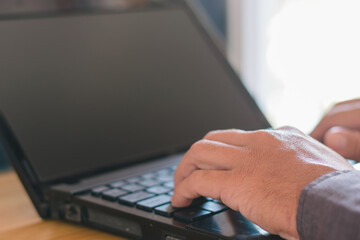 Businessman's hands working with a notebook computer in an office desk or office table.