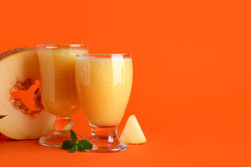 Glasses of tasty melon smoothie and mint on orange background