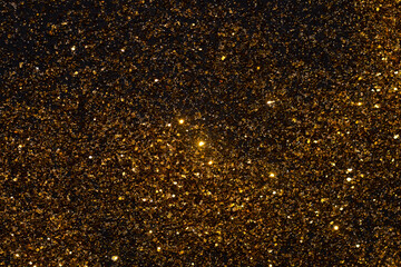 Golden flakes are scattered on the black surface. gold particle for graphic resources.