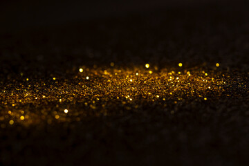 group of golden flakes are scattered on the black surface.gold particle for graphic resources.