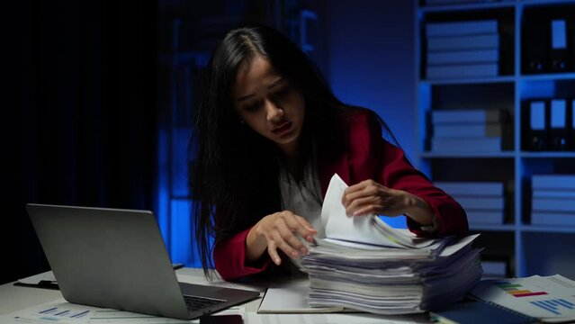 Businesswoman working in piles of paper files Data graph document to find and review cleared tasks still backlog. unsuccessful folder documents at the office desk.