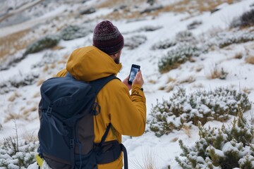 Fototapeta na wymiar hiker using smartphone to navigate snowy terrain