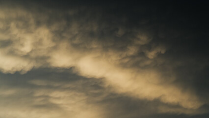 Fototapeta premium Coucher de soleil sous les nuages, révélant de magnifiques reflets jaunâtres sous des nuages de type Mammatus