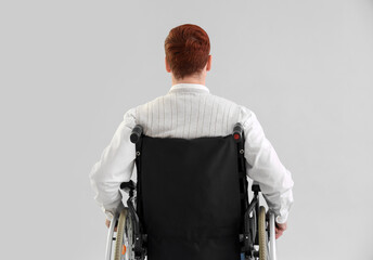 Office worker in wheelchair on light background, back view