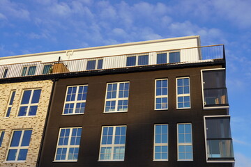 Close up of new modern building of beige and brown brick in Noblessner district. Blue sky and white...