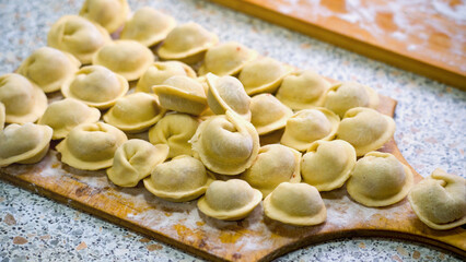 Homemade dumplings close-up, handmade dumplings on a wooden board, selective focus, tinted image, traditional Russian dish